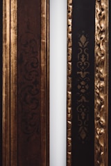 Two decorative frames with ornate patterns are positioned side by side. The left frame features intricate dark swirls and is primarily brown, while the right frame has an embossed gold pattern on a black background. A narrow white strip separates the two frames.