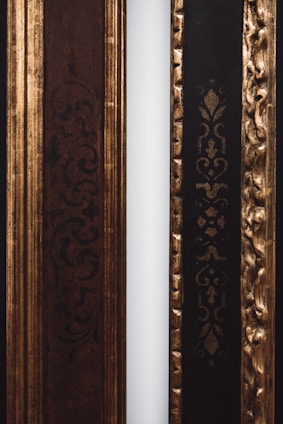 Two decorative frames with ornate patterns are positioned side by side. The left frame features intricate dark swirls and is primarily brown, while the right frame has an embossed gold pattern on a black background. A narrow white strip separates the two frames.