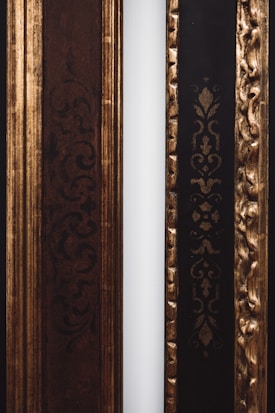 Two decorative frames with ornate patterns are positioned side by side. The left frame features intricate dark swirls and is primarily brown, while the right frame has an embossed gold pattern on a black background. A narrow white strip separates the two frames.