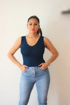 A model wearing a sleek blue shirt standing confidently with hands in pockets.