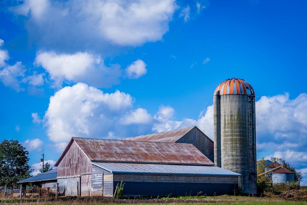 a barn and silo on a farm with a blue sky in the background