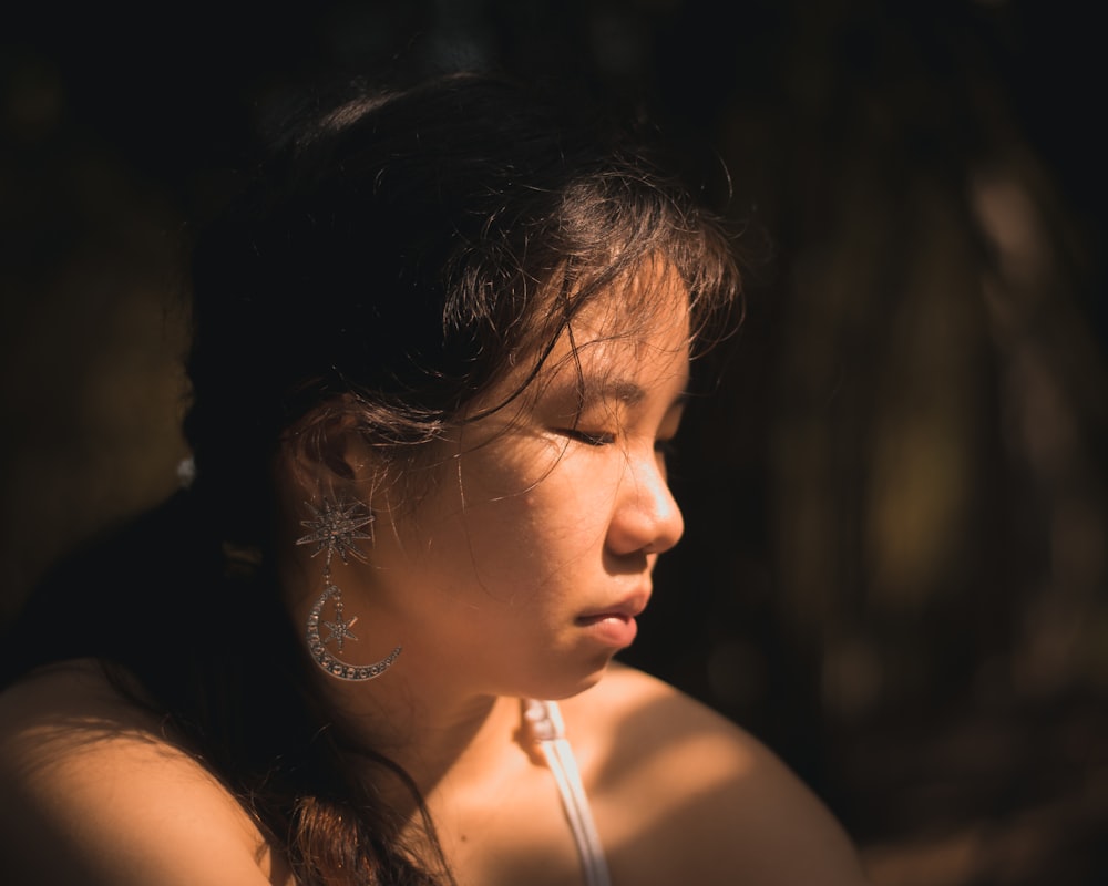 a woman with earrings on her head looking off into the distance