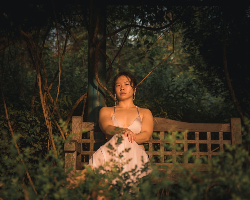 a woman sitting on a wooden bench in the woods