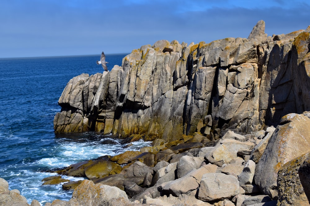 a person standing on top of a rocky cliff next to the ocean