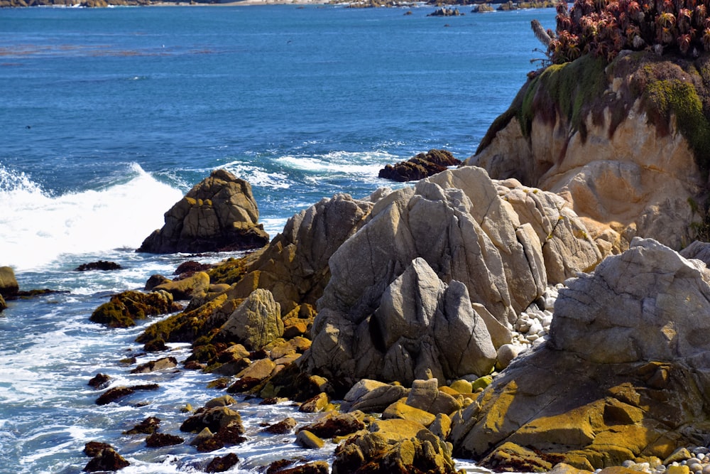um grande corpo de água sentado ao lado de uma costa rochosa