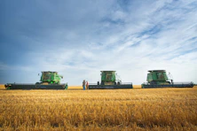 a couple of people standing in a field next to a couple of large green farm