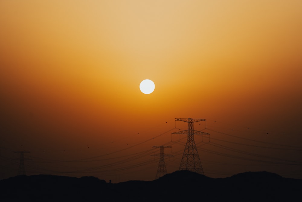 the sun is setting behind power lines in the desert