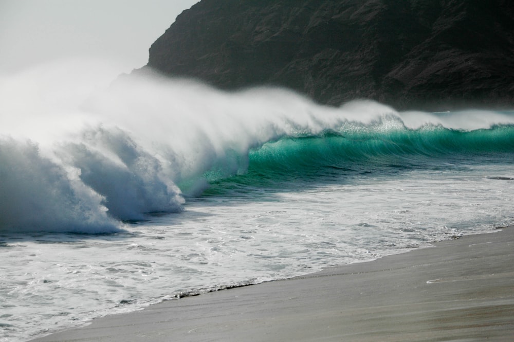 a large wave crashing into the shore of a beach