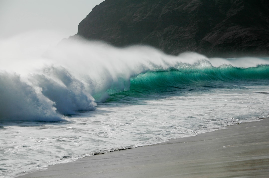 a large wave crashing into the shore of a beach,