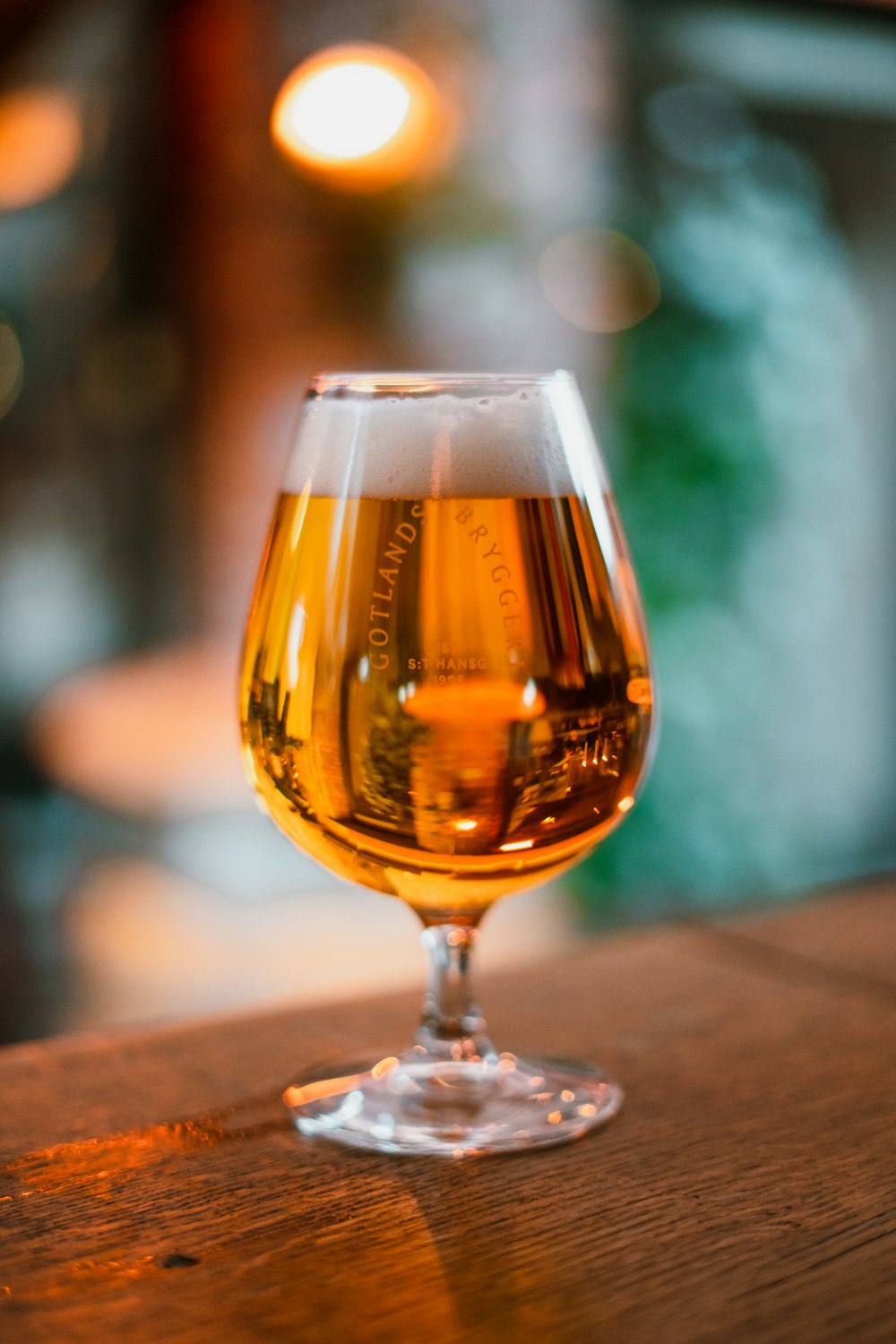 a glass of beer sitting on top of a wooden table