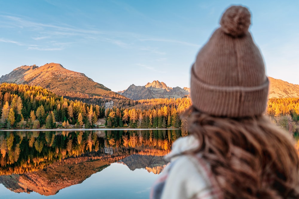 a woman looking out over a lake with mountains in the background