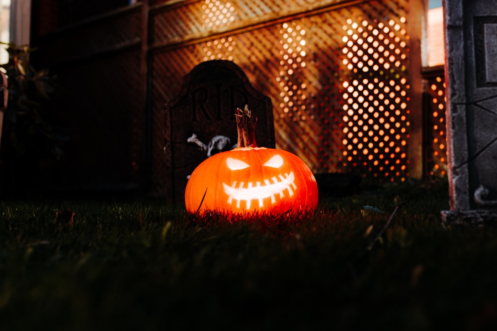 Una calabaza tallada sentada en la hierba frente a una casa