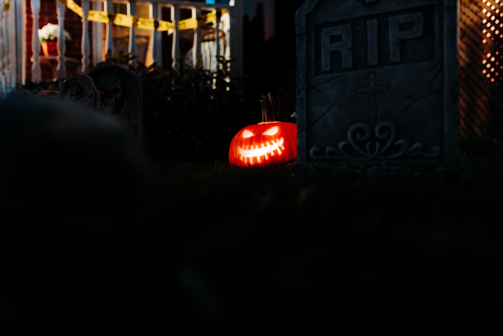 a carved pumpkin sitting in the grass next to a grave