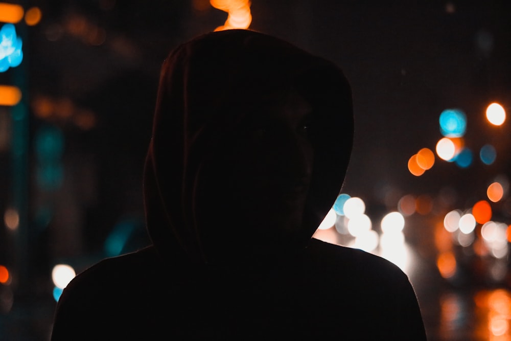 Una persona con una sudadera con capucha parada en la oscuridad