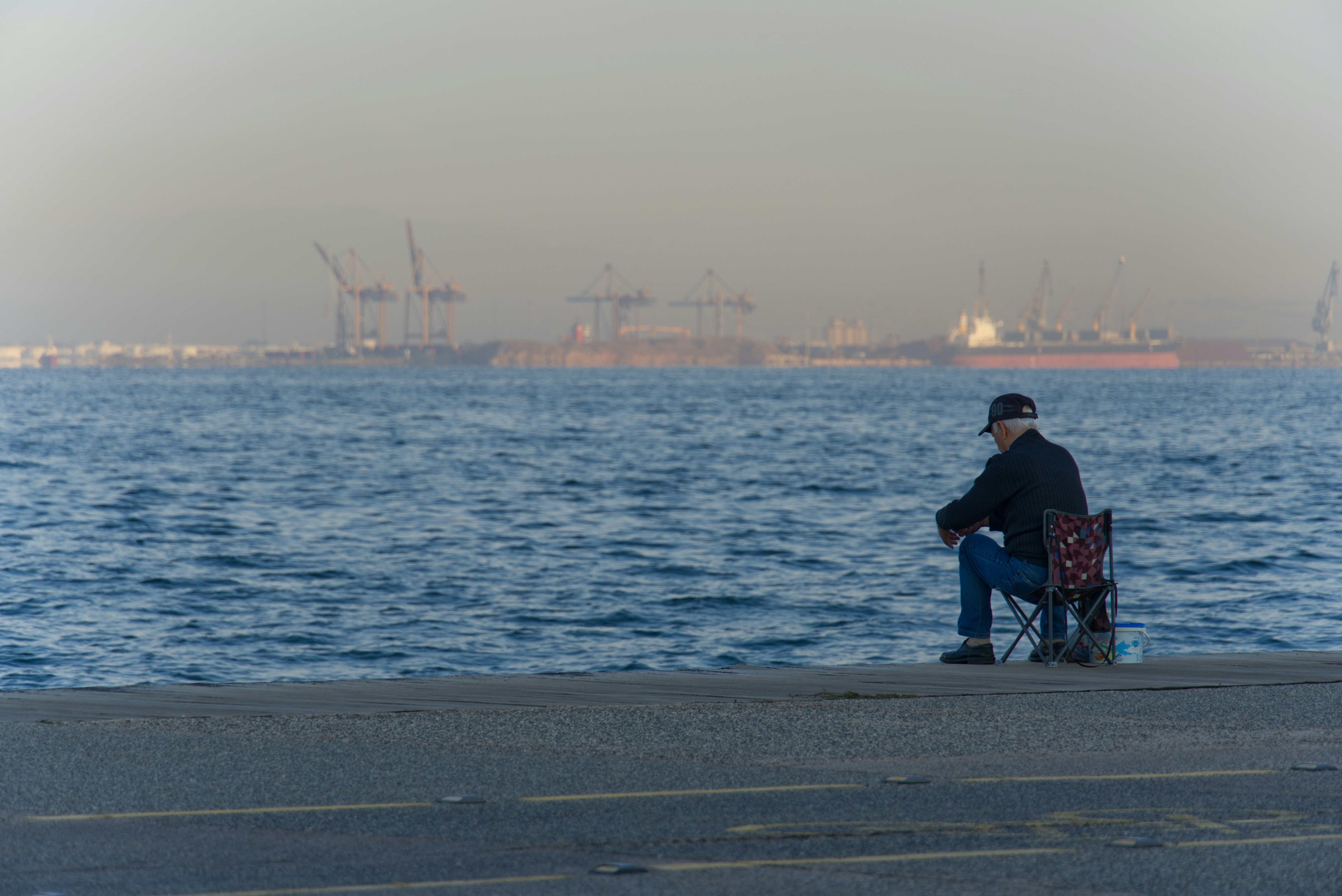 a man sitting on a bench next to a body of water