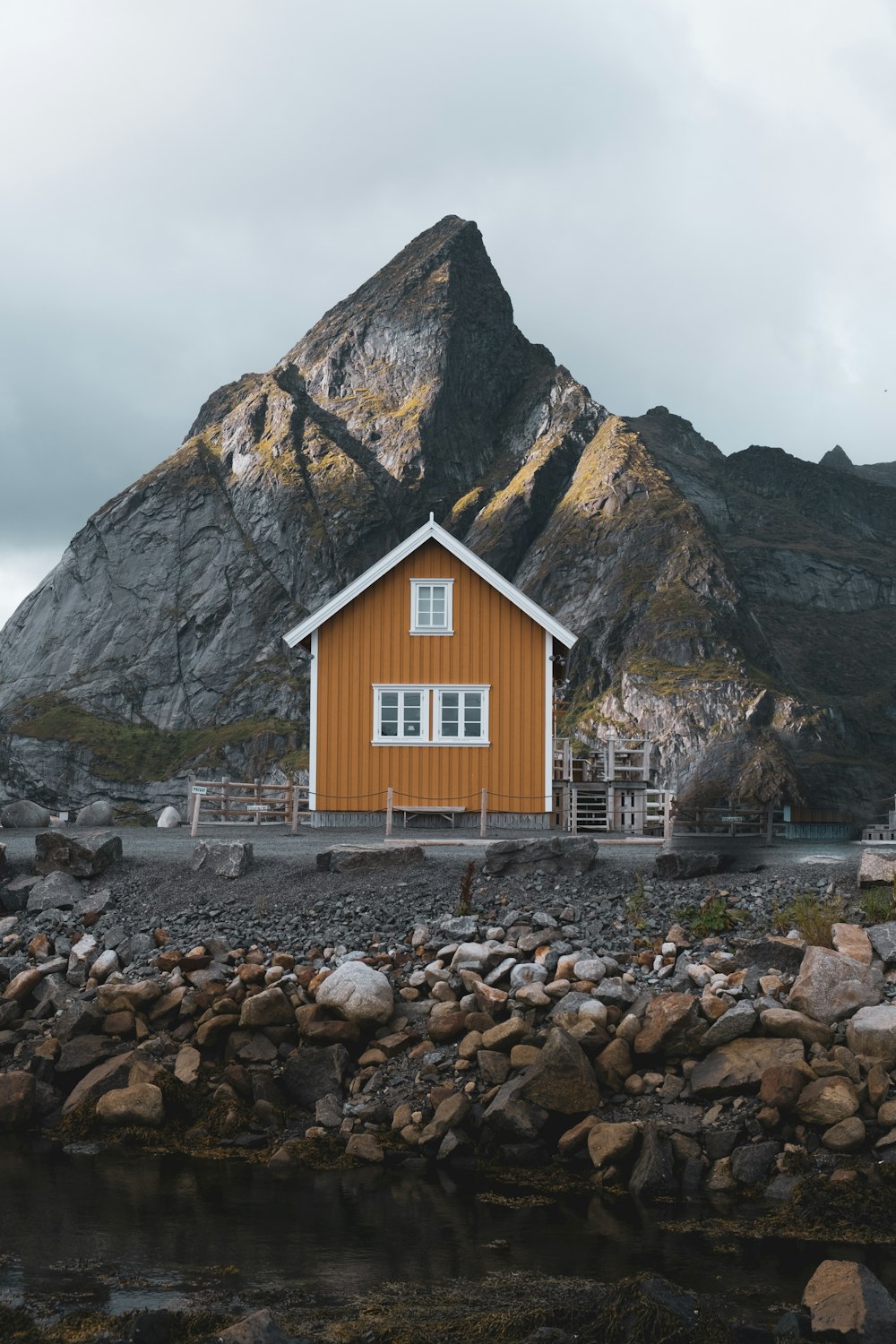Ein Haus an einem felsigen Ufer mit einem Berg im Hintergrund