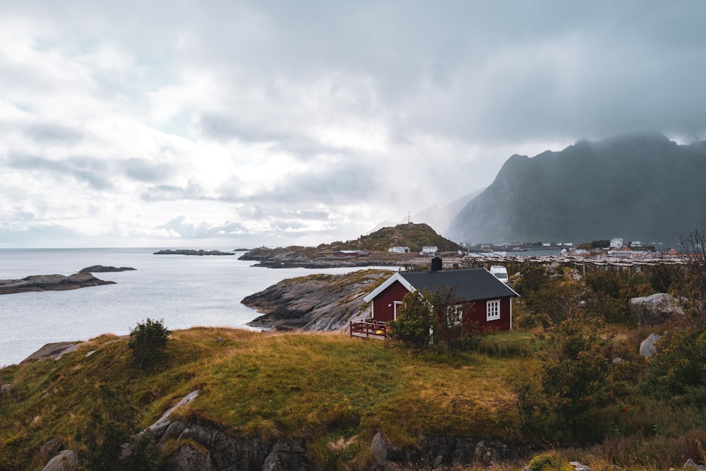 a small red house sitting on top of a lush green hillside