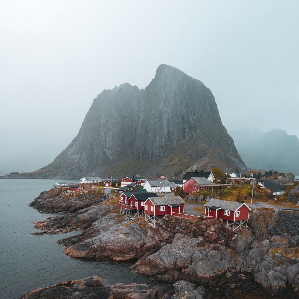 a small village on a rocky shore with mountains in the background