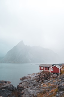 a red house sitting on top of a rocky shore