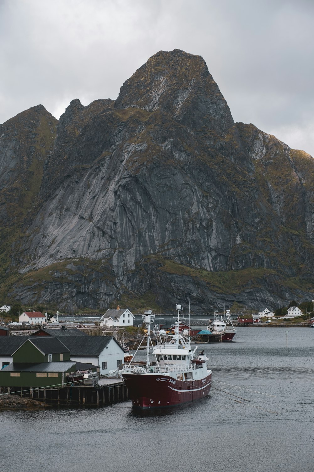 a boat docked in a harbor with a mountain in the background