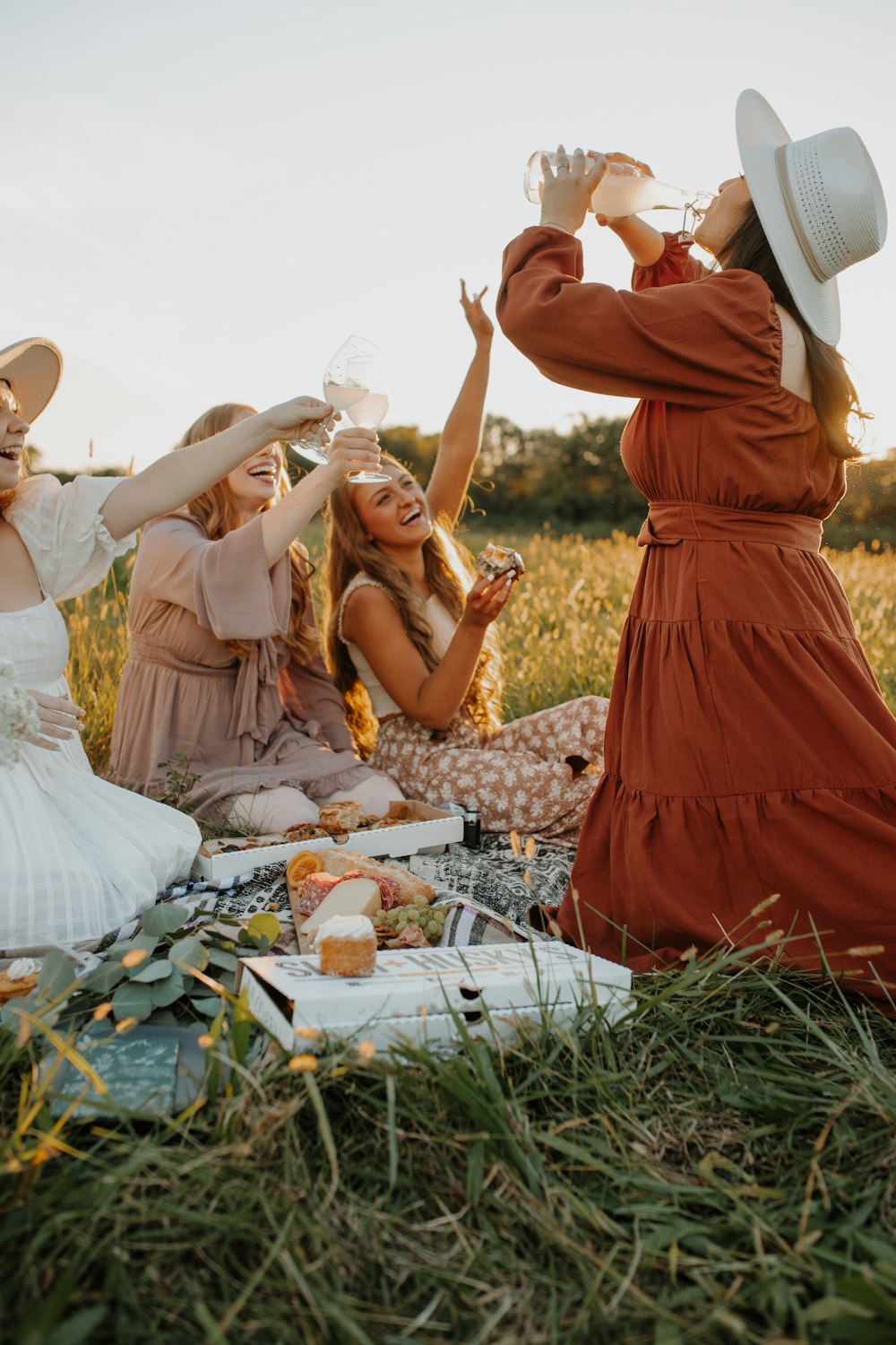 a group of women sitting on top of a grass covered field