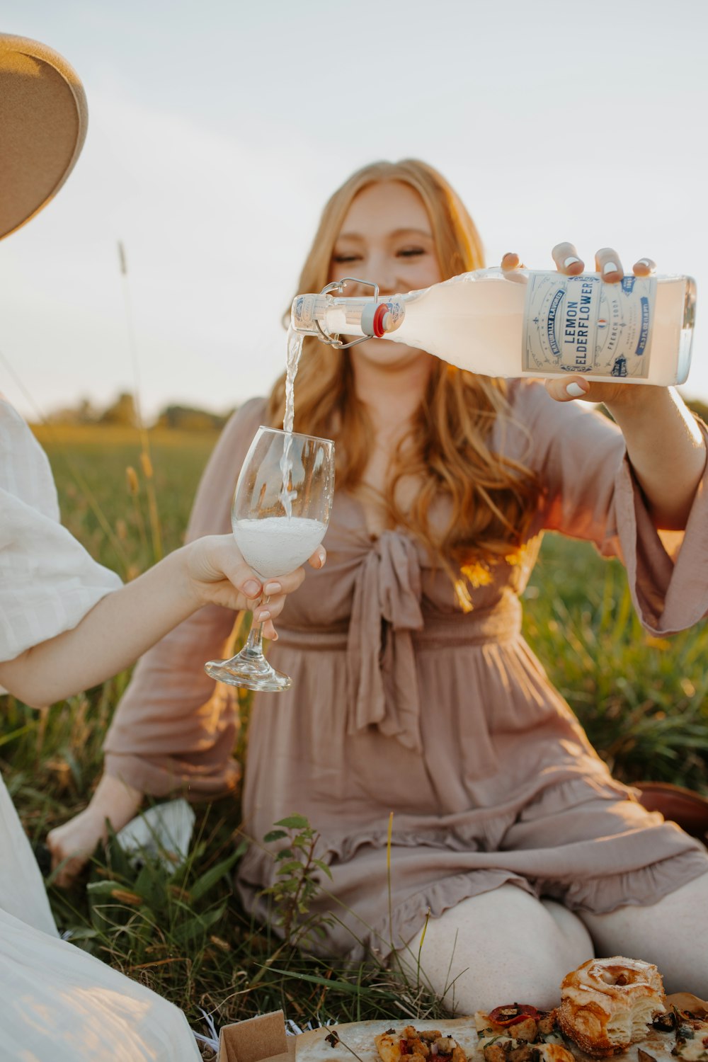 a couple of women sitting on top of a grass covered field