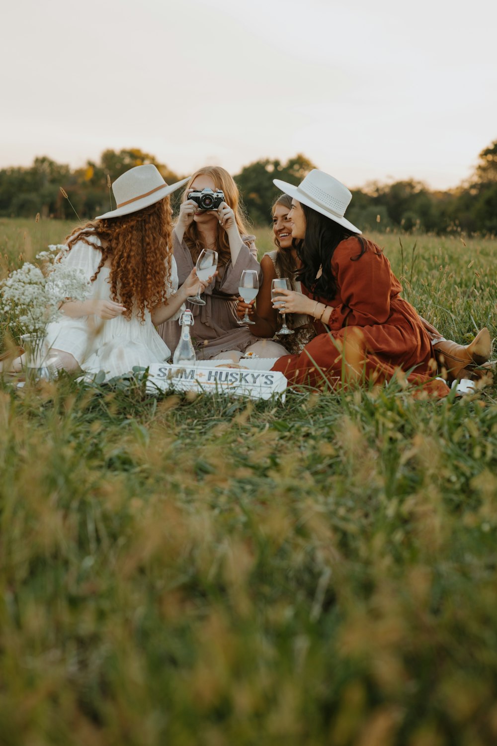 a group of women sitting on top of a lush green field