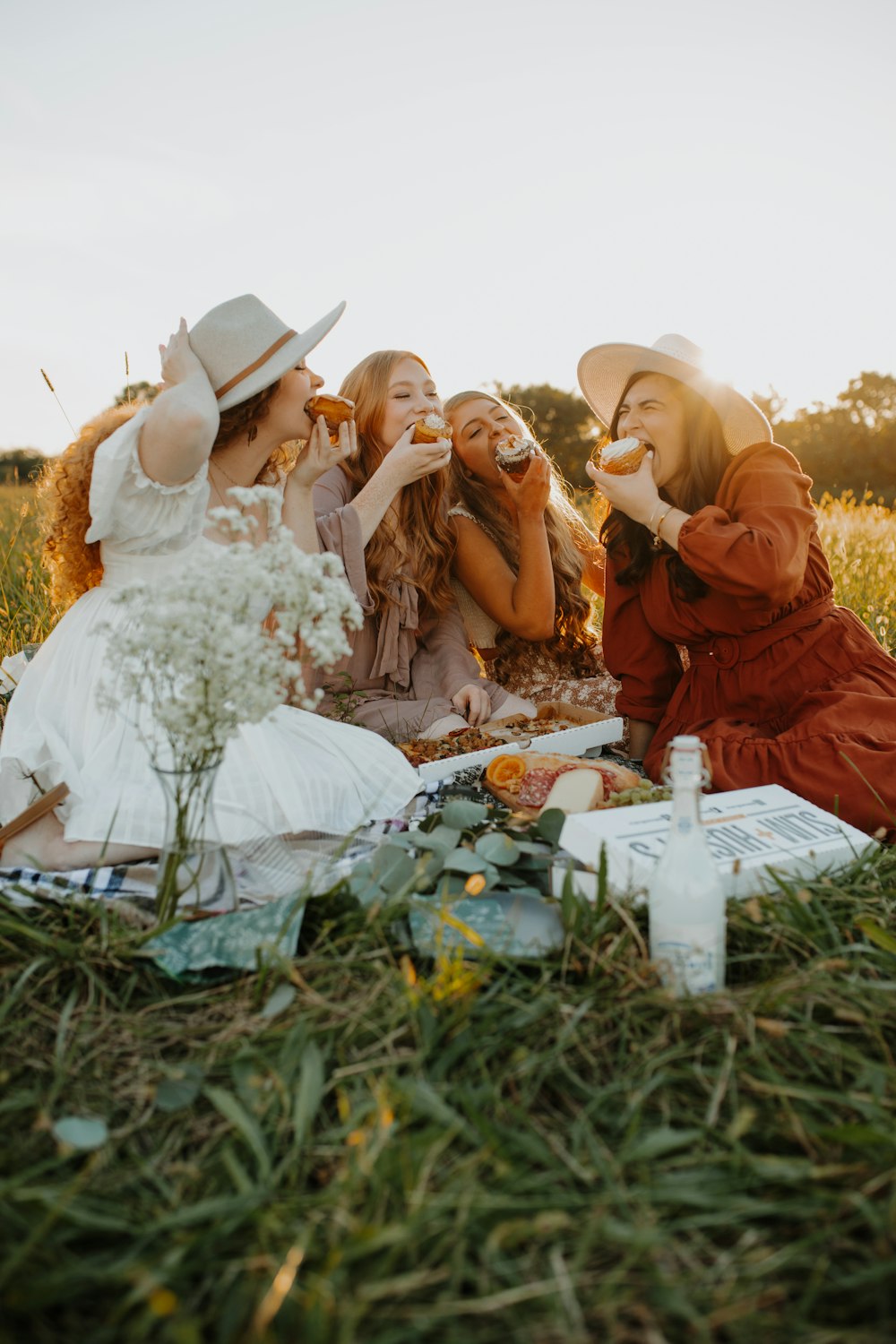 a group of women sitting on top of a grass covered field