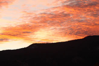 Sunset paints the jagged skyline of a dramatic mountain range.