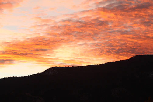 Sunset paints the jagged skyline of a dramatic mountain range.