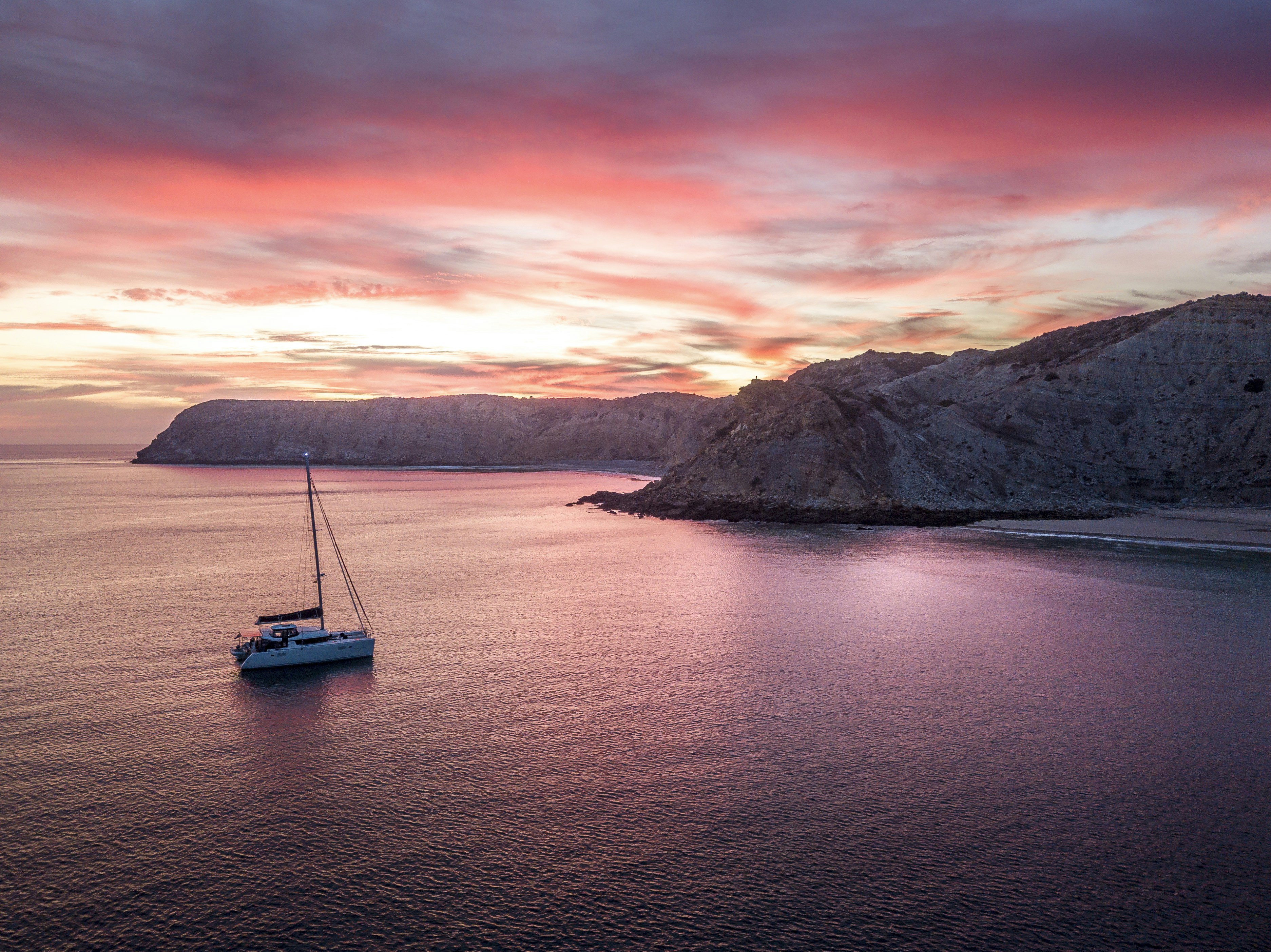 a sailboat floating in the ocean at sunset
