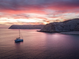 a sailboat floating in the ocean at sunset