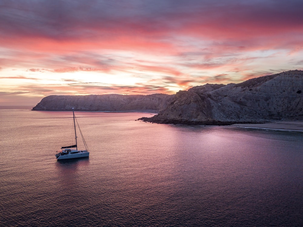 a sailboat floating in the ocean at sunset