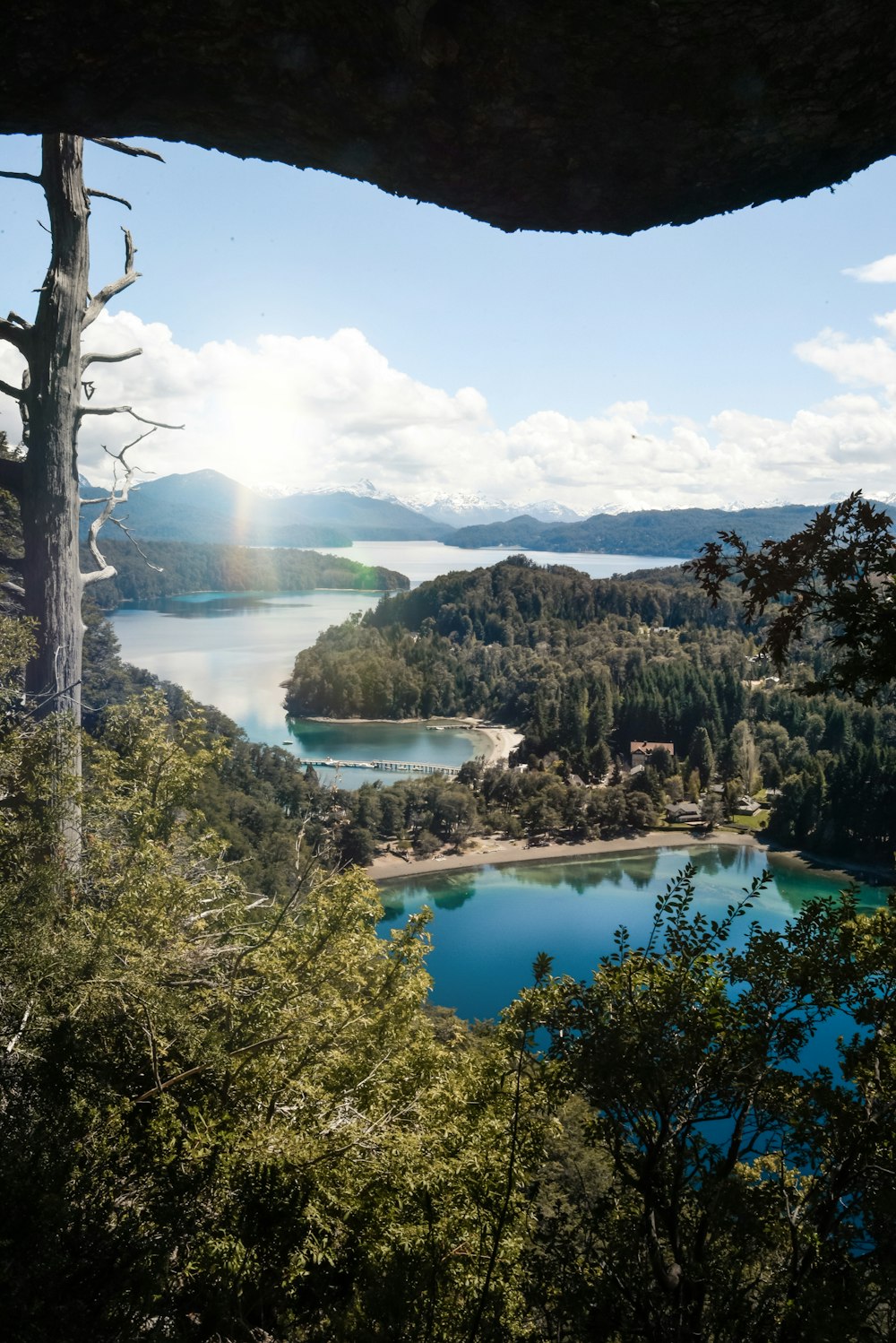 a lake surrounded by trees and mountains under a blue sky