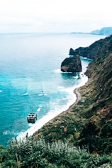 a boat is on the water near a cliff