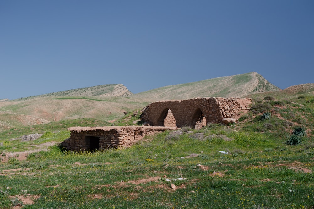 a stone building sitting on top of a lush green hillside