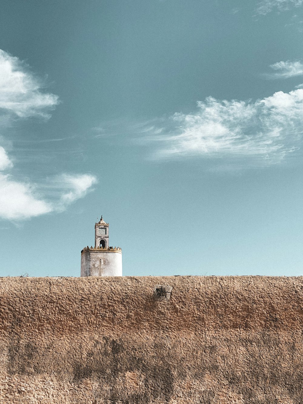 a white tower on top of a grass covered hill