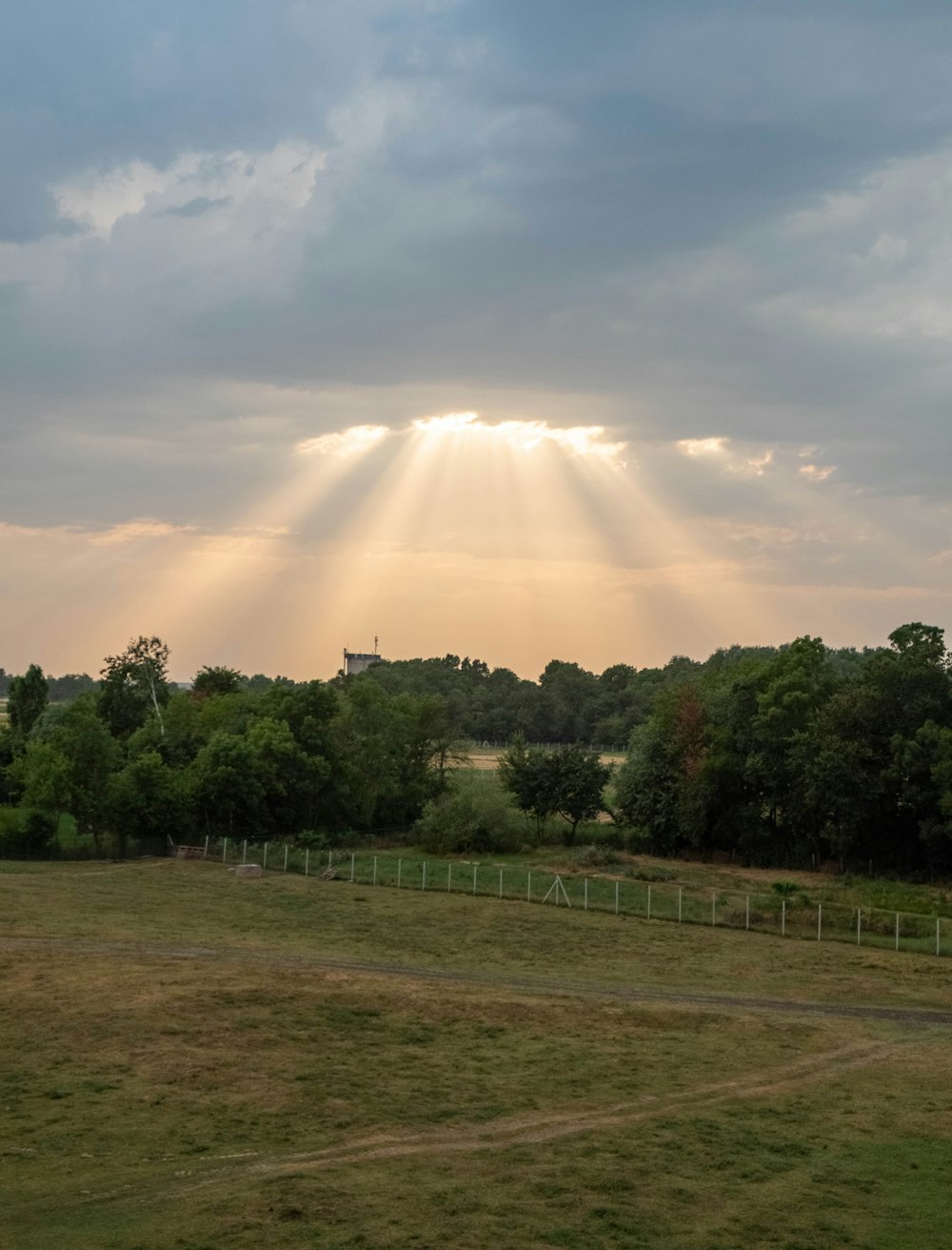 the sun shines through the clouds over a field