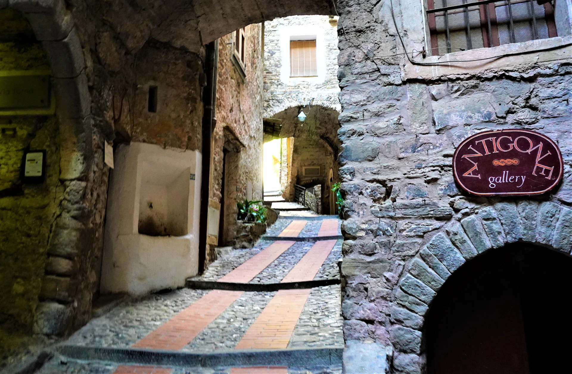 Una strada stretta di pietra fra edifici bassi, in una giornata coperta.