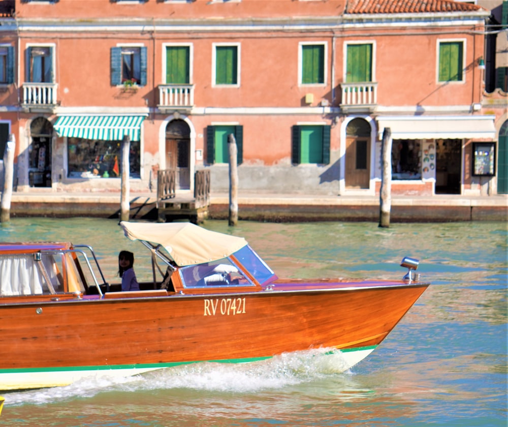 a wooden boat traveling down a river next to a building