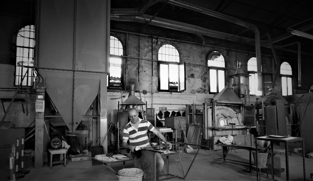 a black and white photo of a man working in a factory
