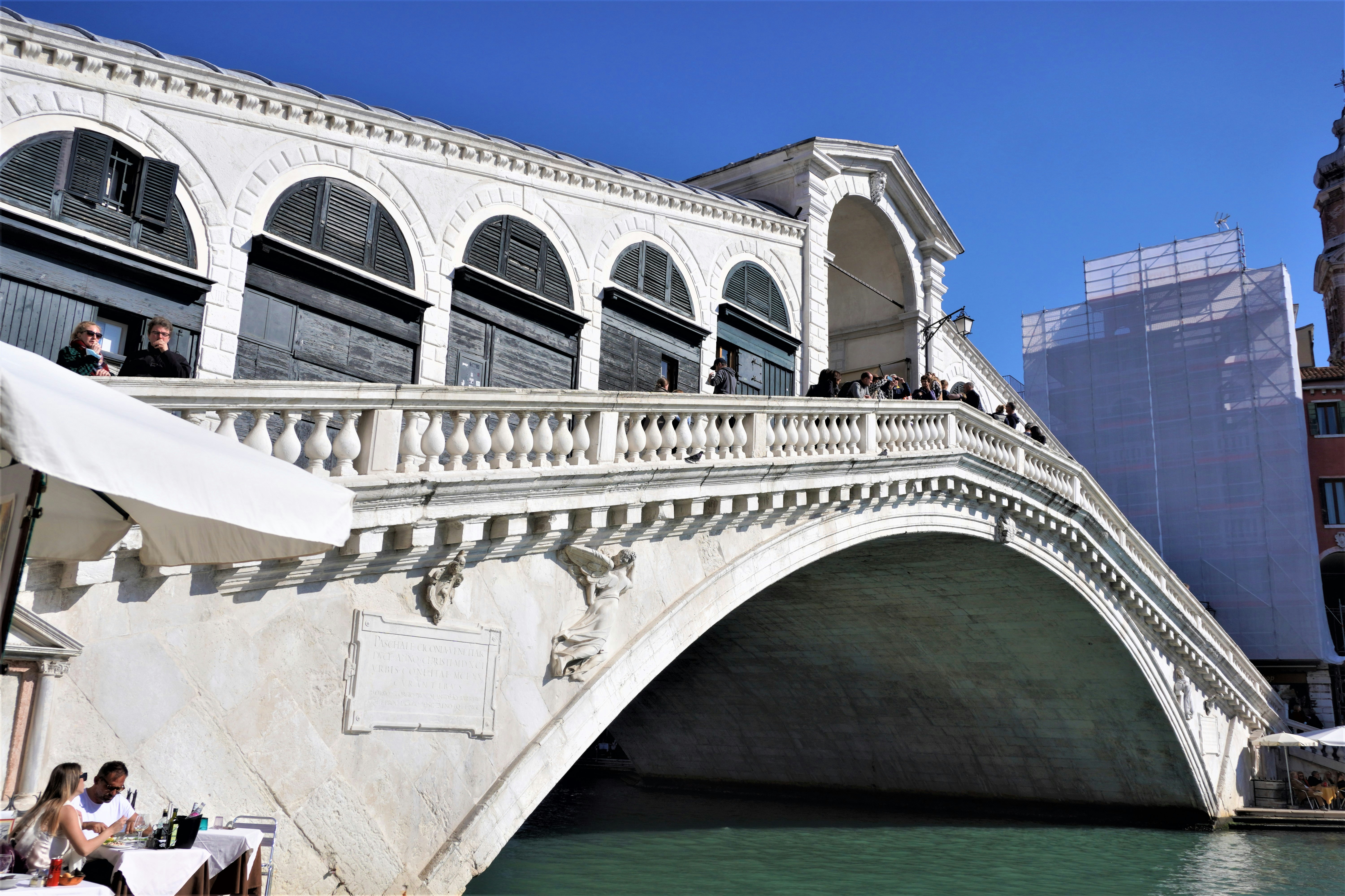 a bridge over a body of water with people sitting on it, bridge, river, architecture, water, italy, venice, rialto, arch, europe, city, travel, tourism, landmark, france, building, stone, london, sky, canal, night, venezia