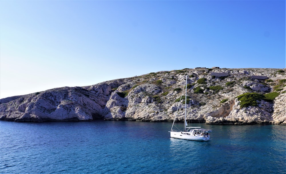 a sailboat in the water near a rocky island