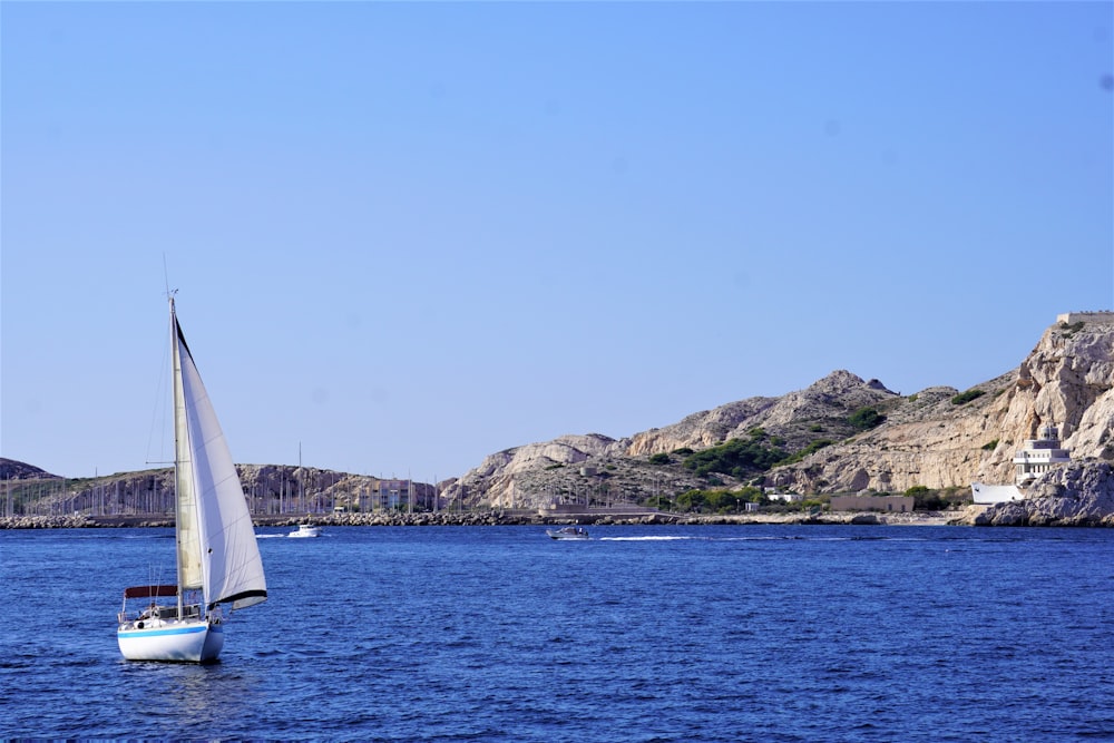 a sailboat in a body of water with mountains in the background