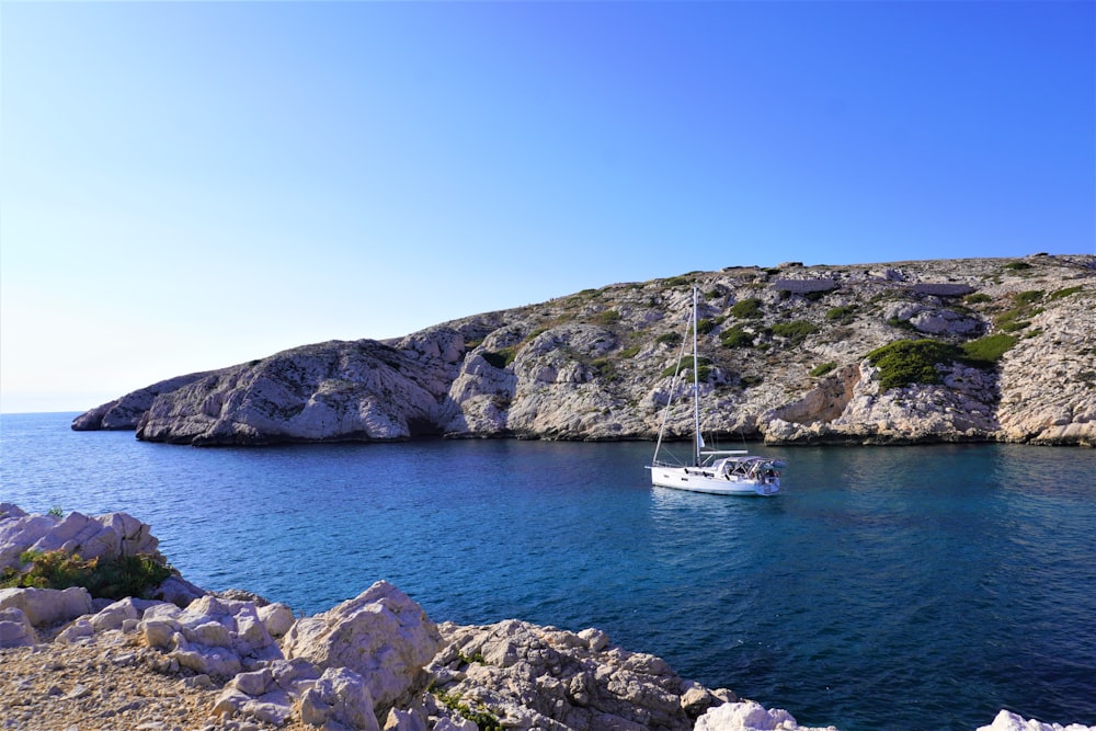 a sailboat in the water near a rocky shore