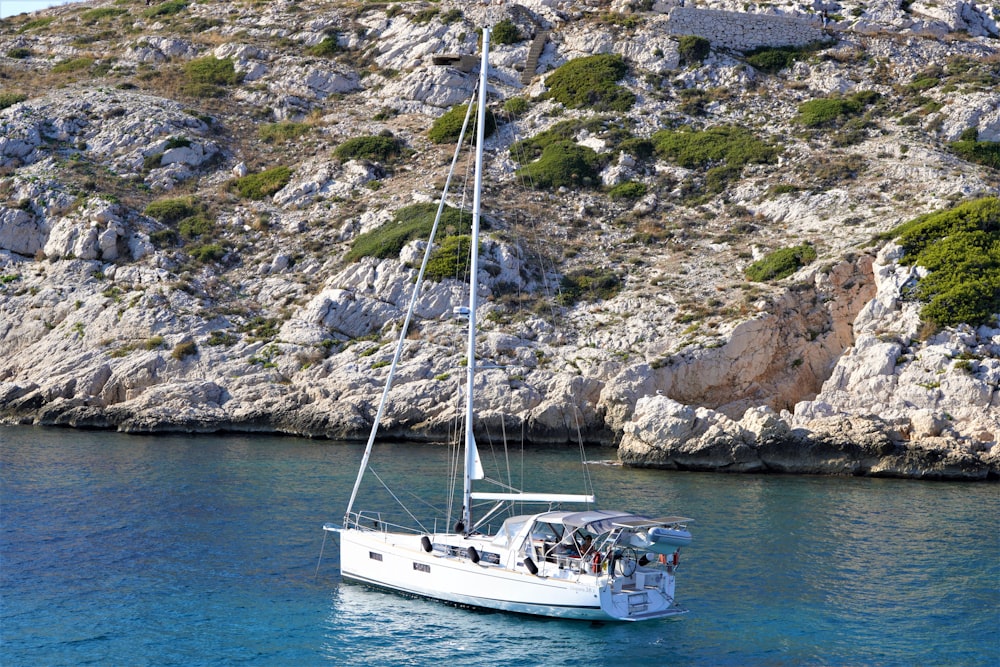 a sailboat in the water near a rocky shore