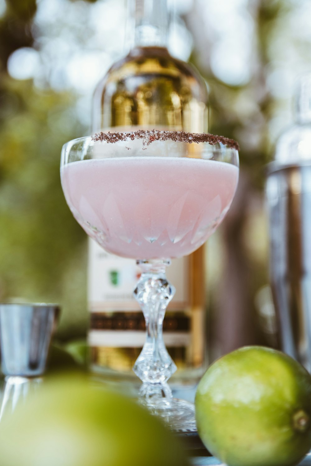 a glass filled with a liquid next to a bottle of alcohol