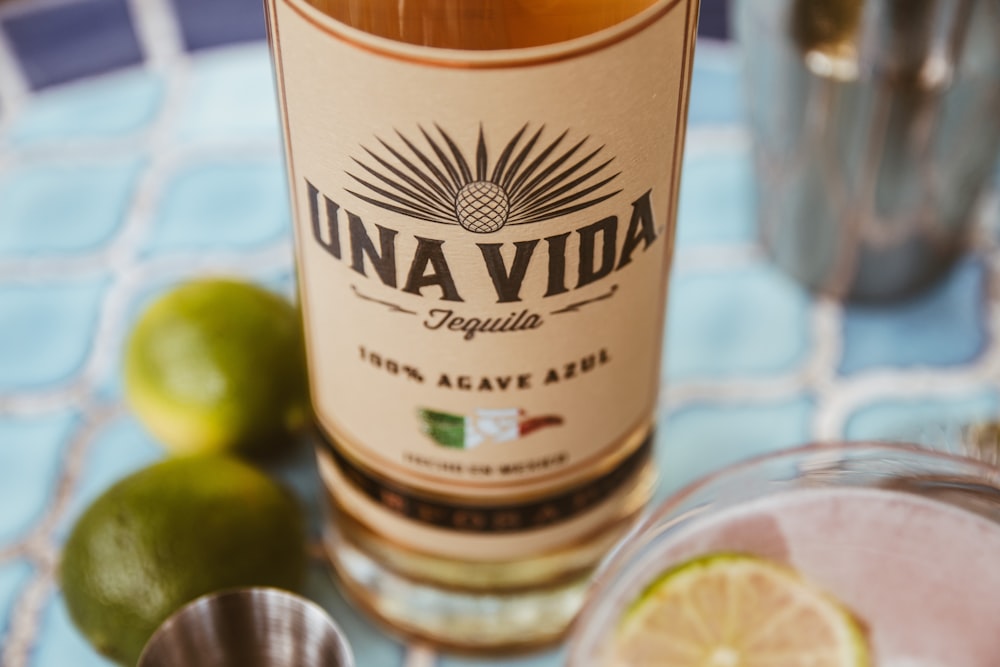une bouteille de tequila à côté de limes sur une table