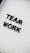 Black plastic letters forming the words 'TEAM WORK' are placed on a white letter board with horizontal grooves.