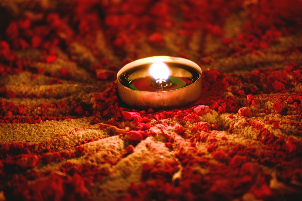 a lit candle sitting on top of a red blanket